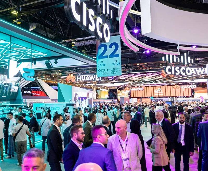 GITEX Global exhibition floor crowded with visitors, Cisco and Huawei stands overhead, hall 22 signage